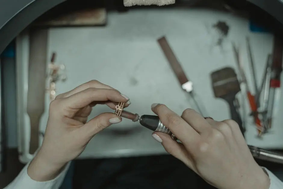 Hands finishing a piece of jewellery at the workshop bench